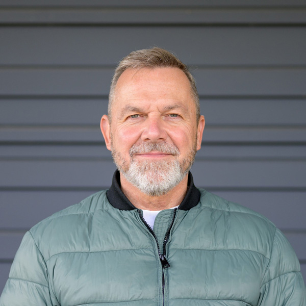 A 50-60 year old white man with grey hair, mustache, and beard wearing a grey jacket.